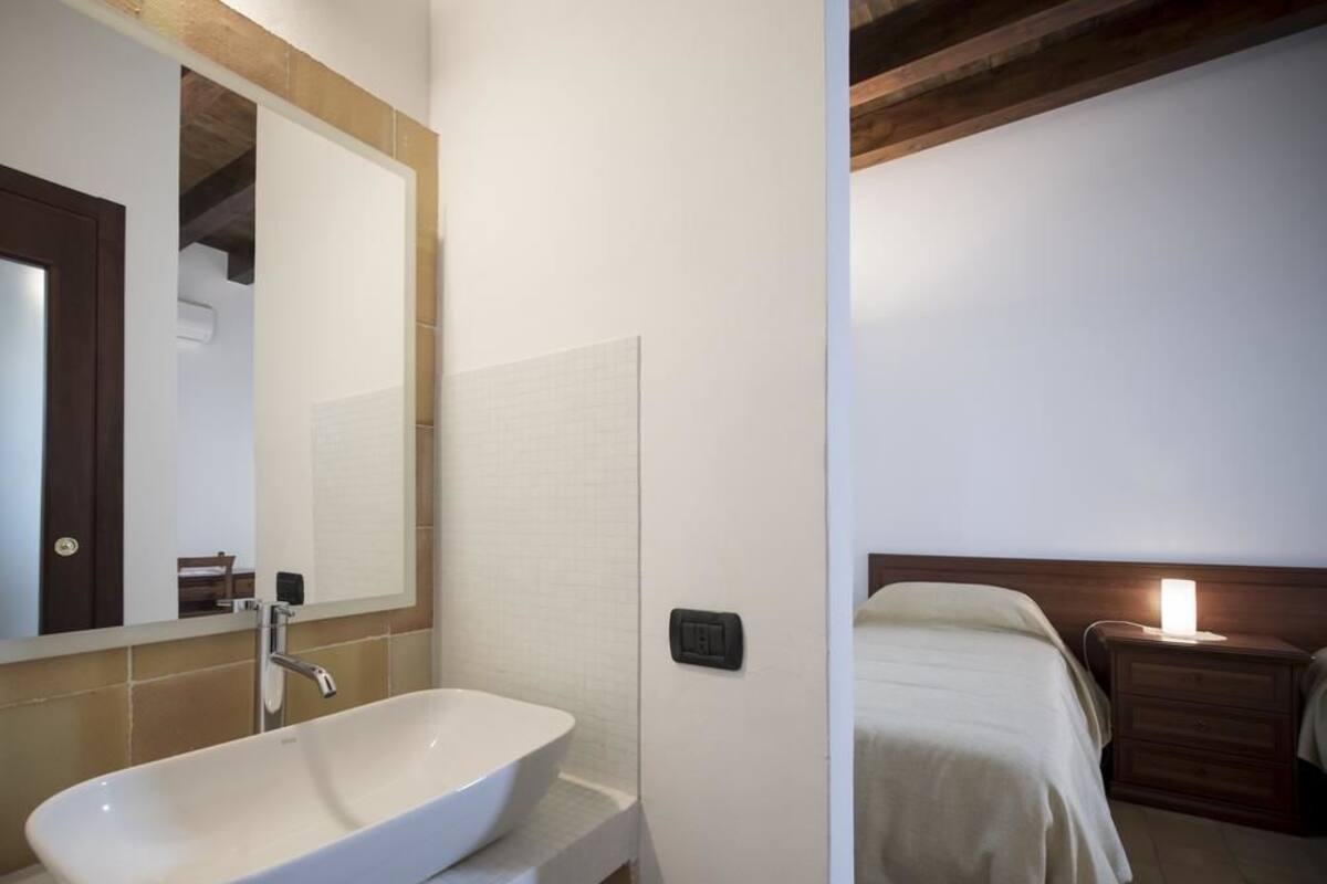 A bathroom with a white sink, a mirror, and a wooden ceiling.