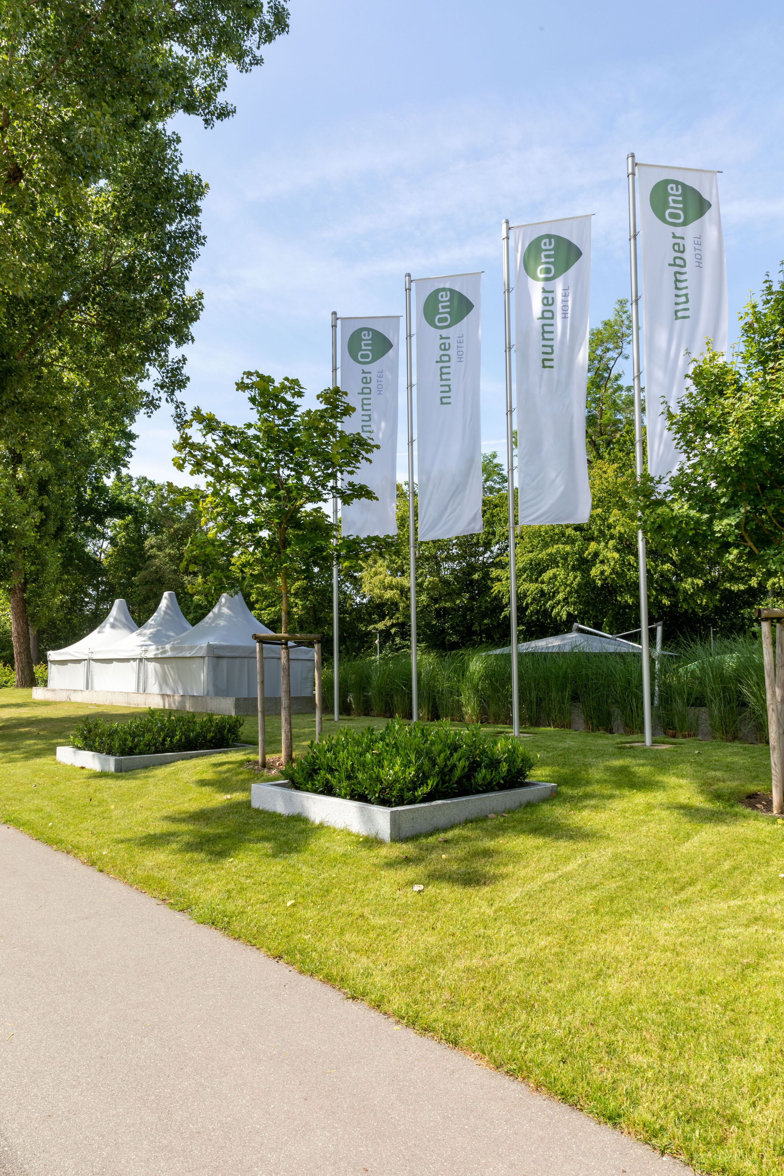 A garden area with white tents and flags for Number One Hotel.