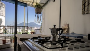 A kitchen with a gas stove, a coffee maker, and a view of a mountain. - Taggarb B&B (Naples)