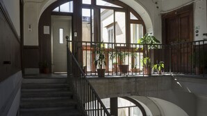 A grand staircase with a wrought iron railing, leading to a balcony with potted plants and a view of the street. - Taggarb B&B (Naples)