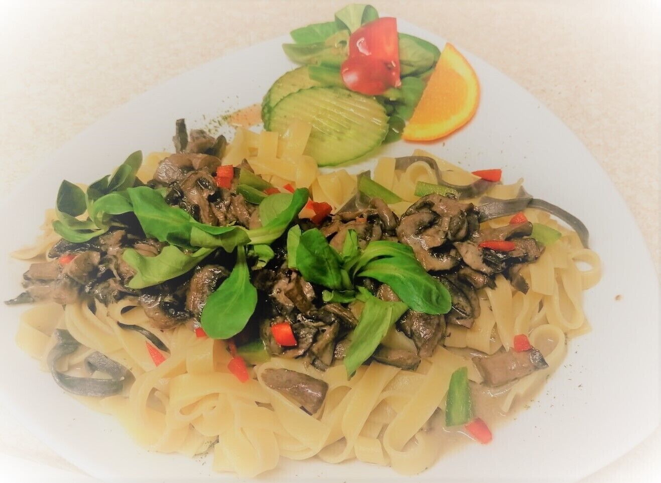 Un plato de pasta con champiñones, espinacas y pimientos rojos.