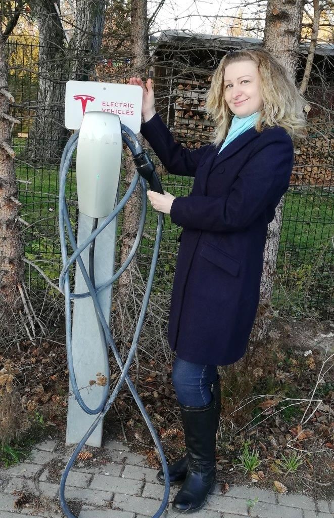 A person charging an electric vehicle at a charging station.