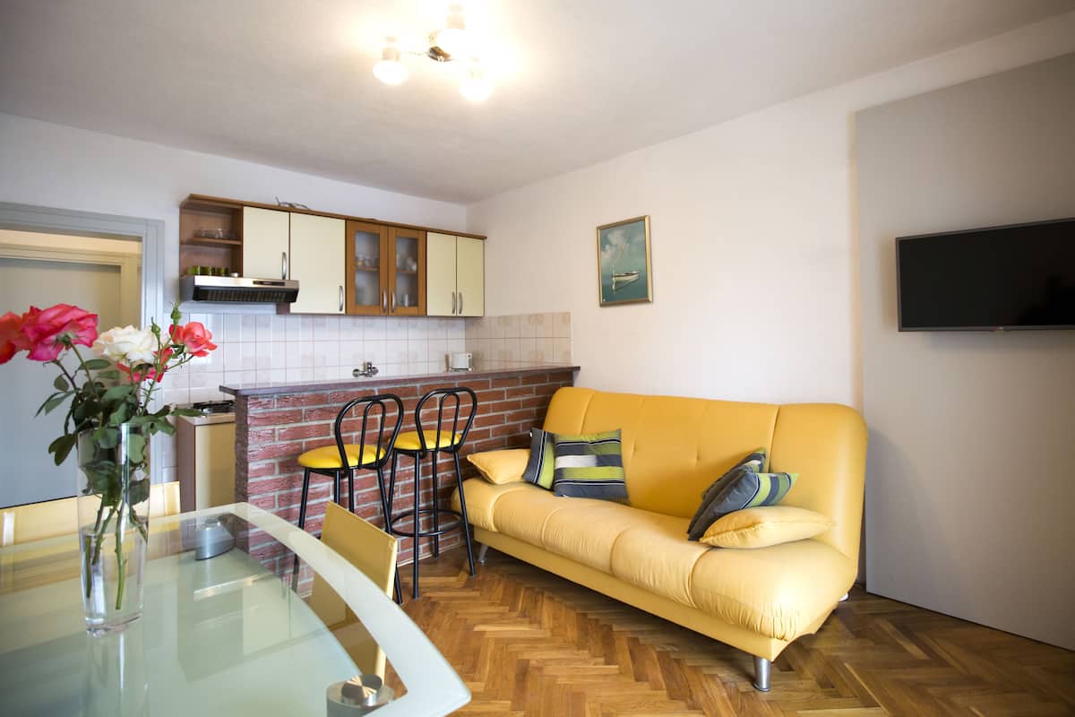 A compact living space with a dining area, a sofa, and a kitchen.