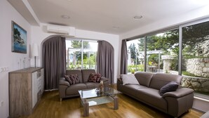 A modern living room with two sofas, a glass coffee table, and a wooden cabinet. - Apartments Bago (Split)