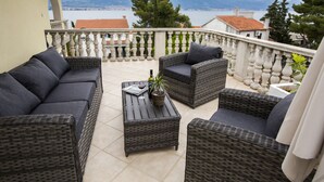 A balcony with wicker furniture, a potted plant, and a bottle of wine. - Apartments Bago (Split)