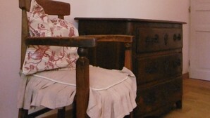 Une pièce avec une chaise en bois, une commode et un miroir au mur.