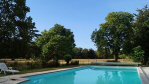 Une piscine rectangulaire dont les bords sont recouverts de carreaux, entourée d’une terrasse dallée.