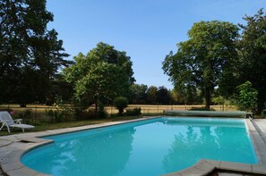Una piscina al aire libre, sombrillas, sillones reclinables de piscina