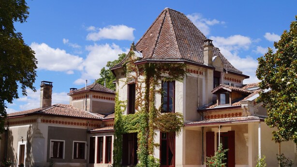 Un grand bâtiment historique, doté d’une tour imposante, de nombreuses fenêtres et d’un porche abrité.