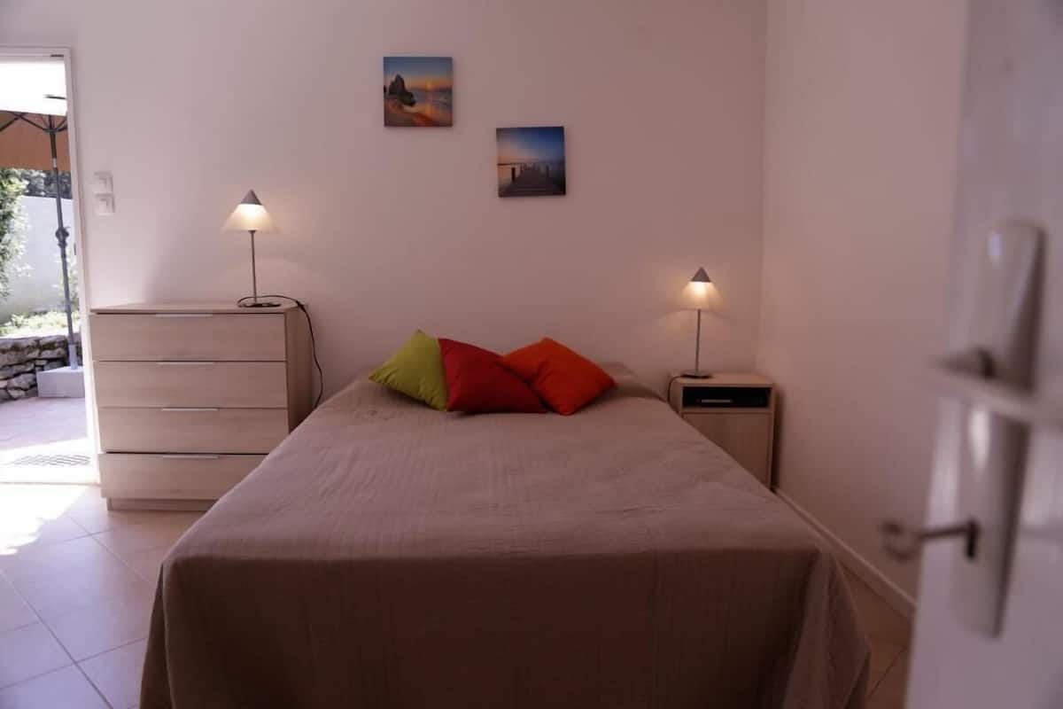 Une chambre à coucher comprenant un lit, deux lampes de chevet, une commode et deux tableaux accrochés au mur.