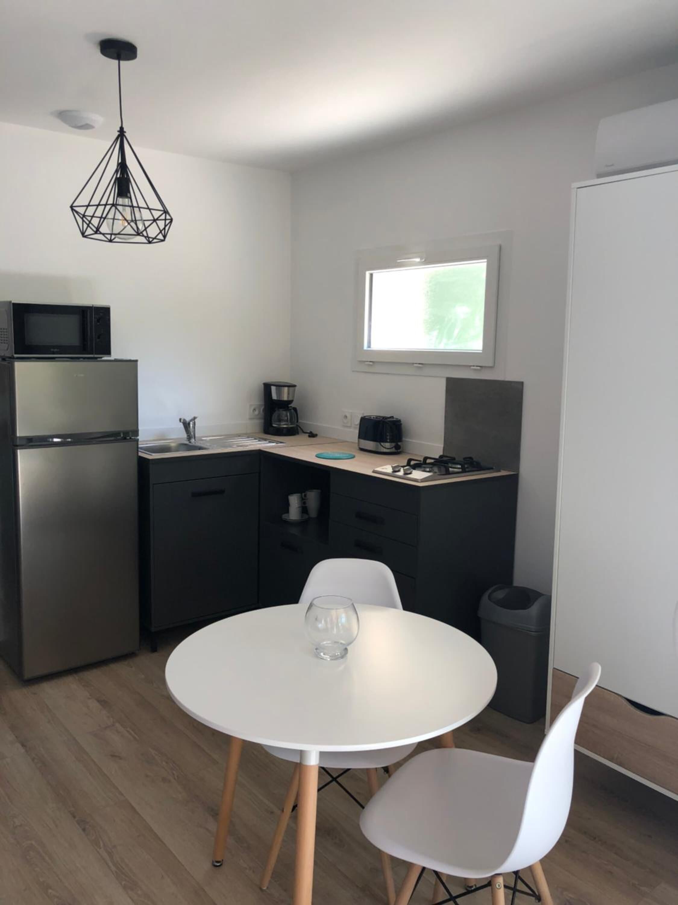 A compact kitchen with a refrigerator, microwave, coffee maker, and a window.