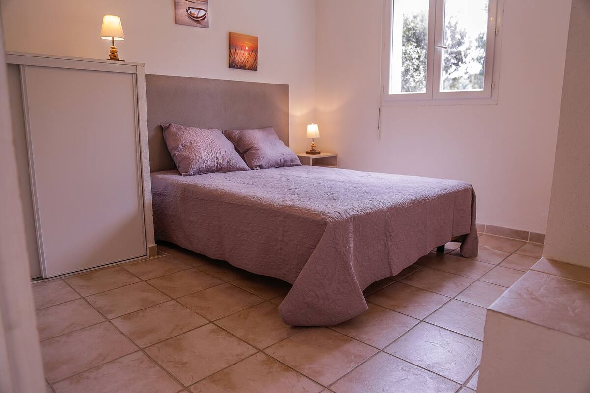 Une chambre à coucher avec un lit, deux lampes de chevet, une fenêtre et une porte.