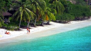 A beach with white sand, turquoise water, and palm trees. - OK2 Bungalow (Koh Tao)
