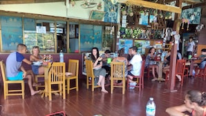 A restaurant with wooden chairs and tables, a counter with a menu, and a wall with marine life decorations. - OK2 Bungalow (Koh Tao)