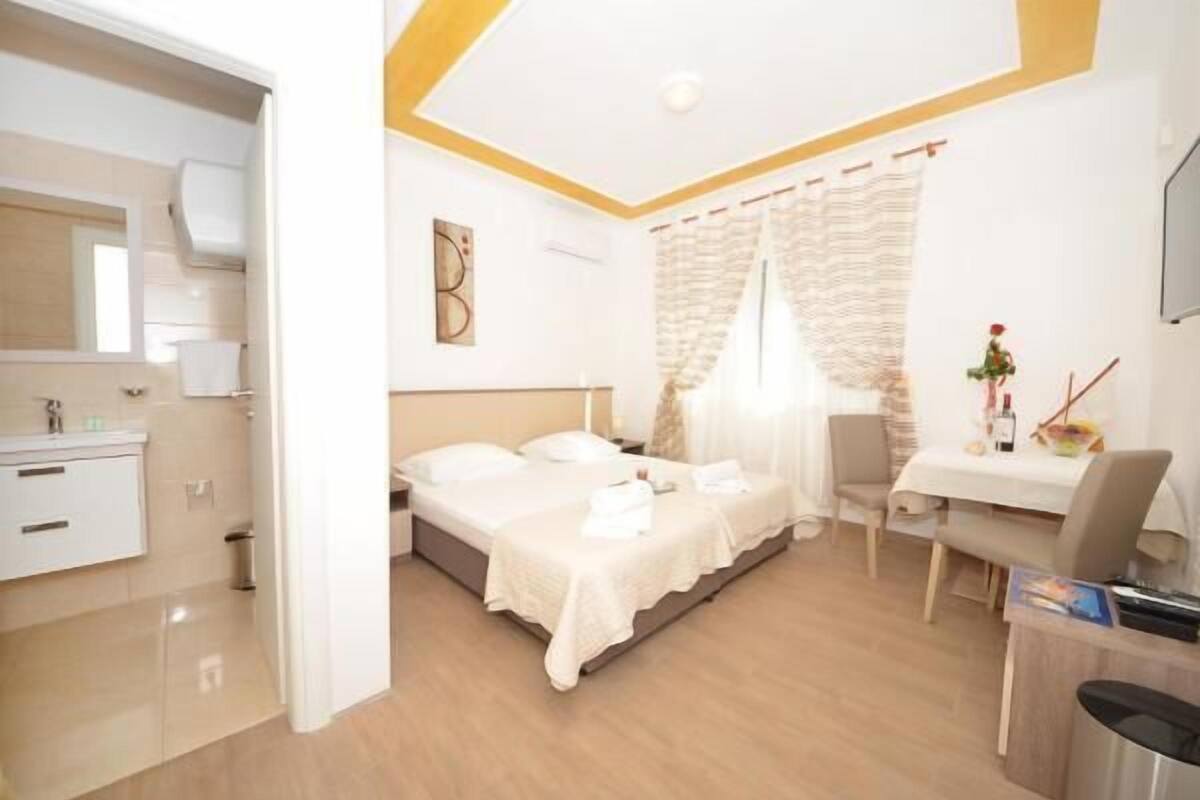 Ein Hotelzimmer mit Bett, Nachttisch, Stuhl und Schreibtisch mit Sitzgelegenheit.