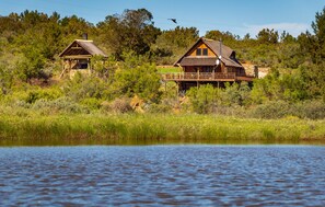 Two rustic cabins by a lake surrounded by dense greenery. - Mountain Cabin (Wolseley)