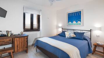 Une chambre à coucher comprenant un lit, un bureau, une chaise, une fenêtre et un ventilateur de plafond.