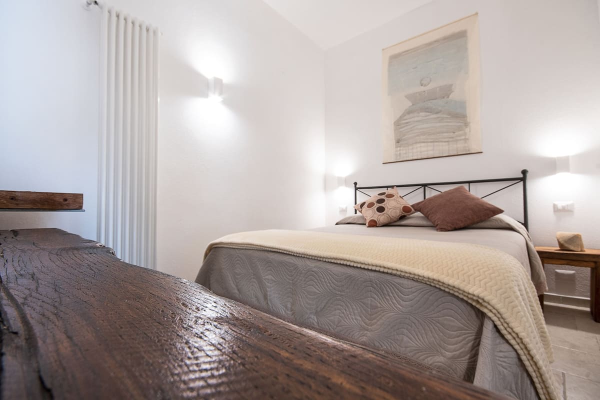 Ein Schlafzimmer mit einem hölzernen Kopfteil, einem Bett mit einer gesteppten Decke, einem Nachttisch und einer Wandleuchte.