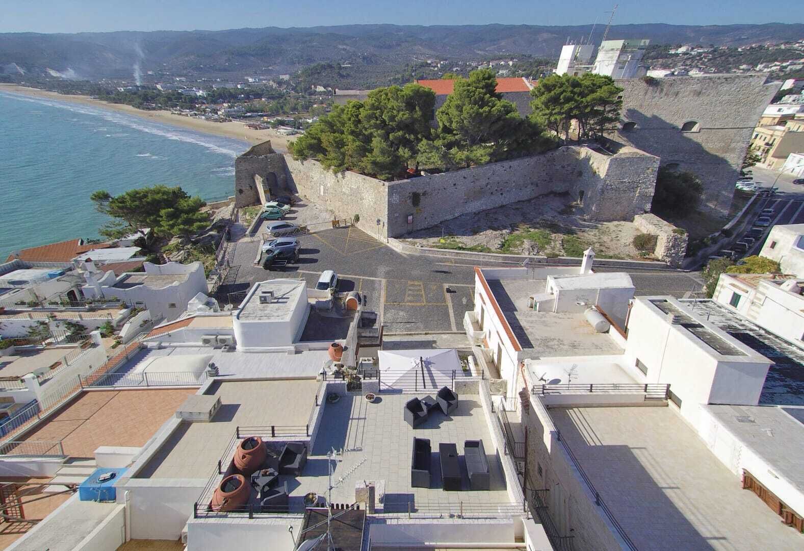 Una terrazza sul tetto con vista sul mare e un'antica muratura in pietra.
