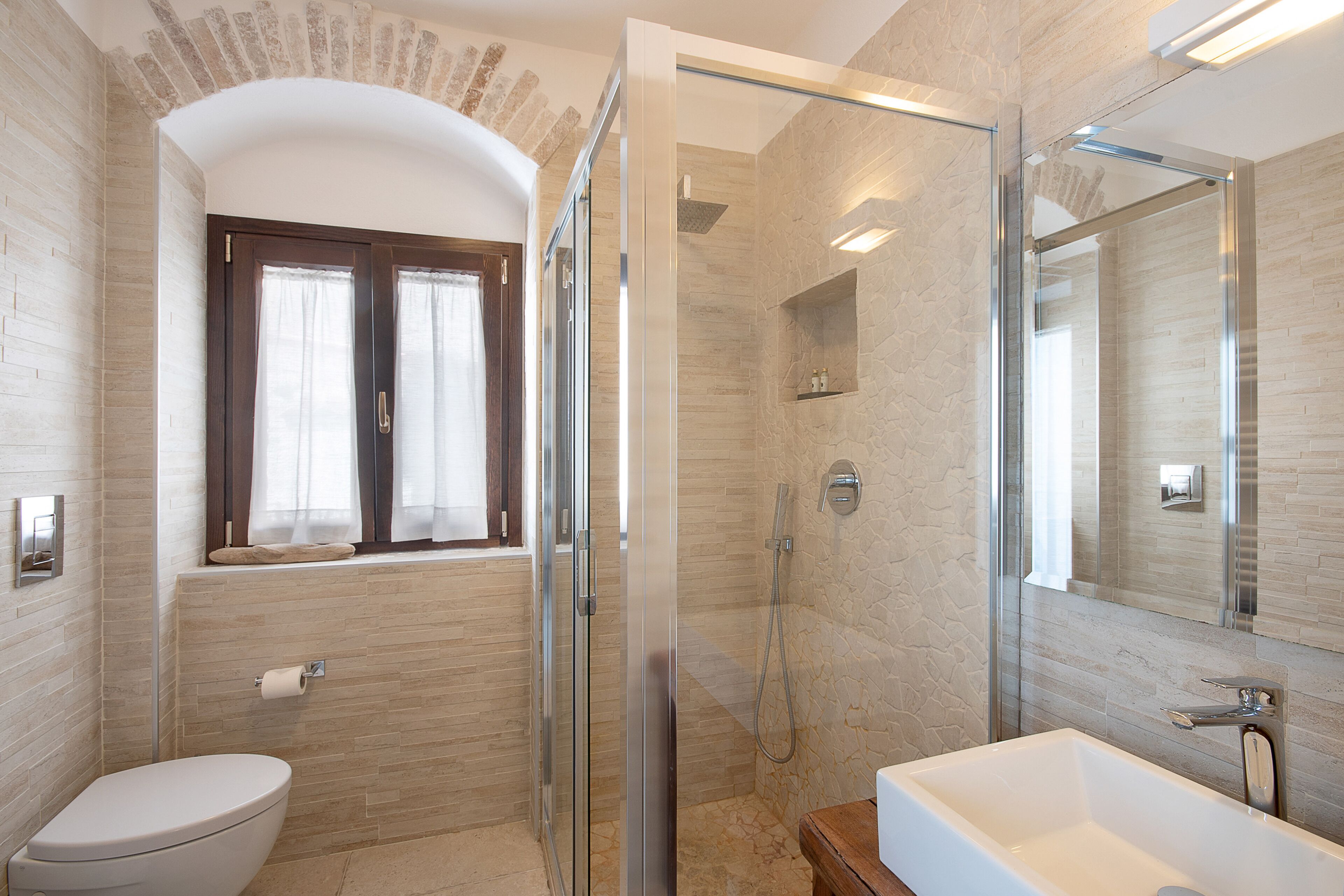 Une salle de bain moderne dotée d’une douche à parois de verre, de toilettes et d’un lavabo.