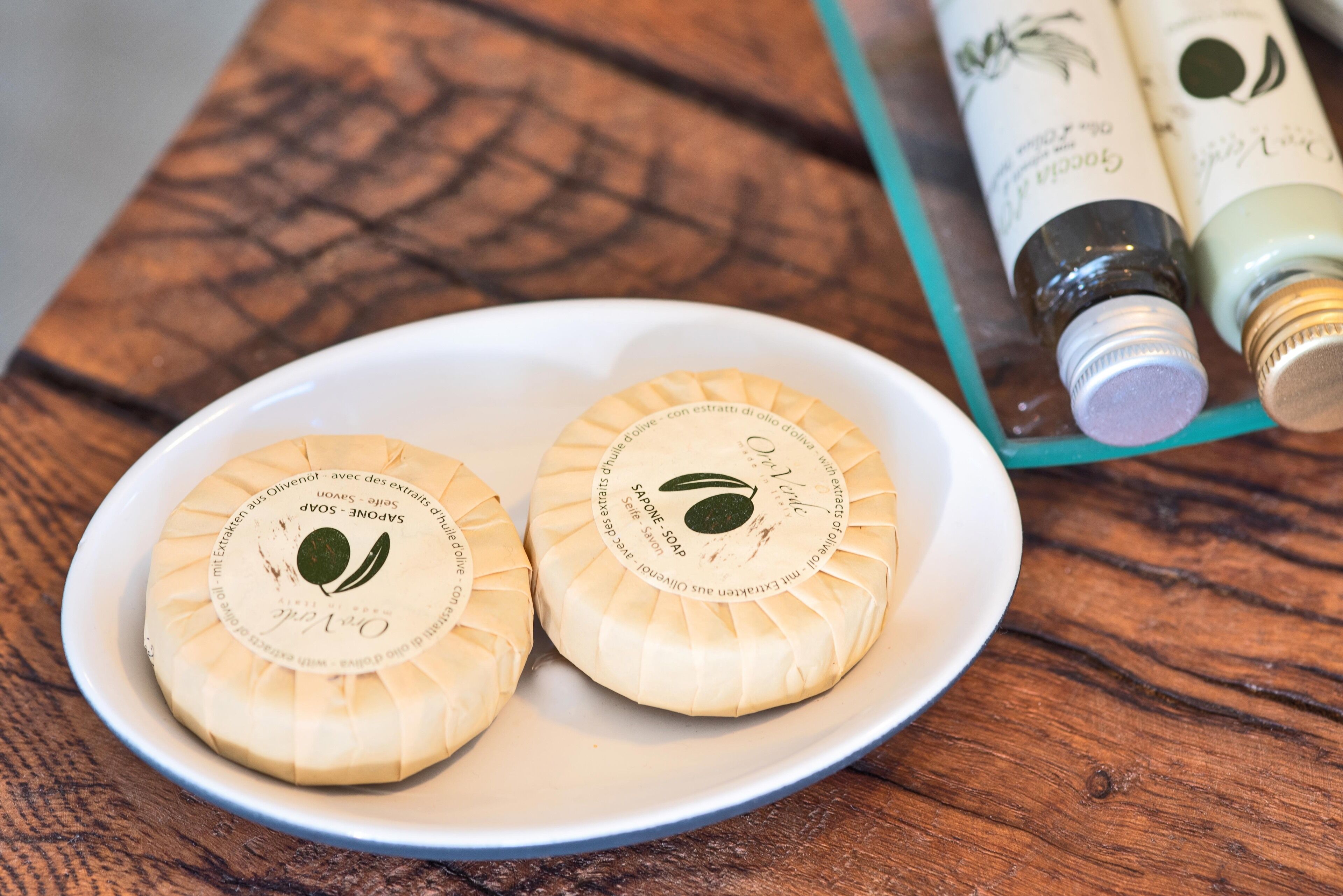 Two round soaps on a white plate with a wooden table background.