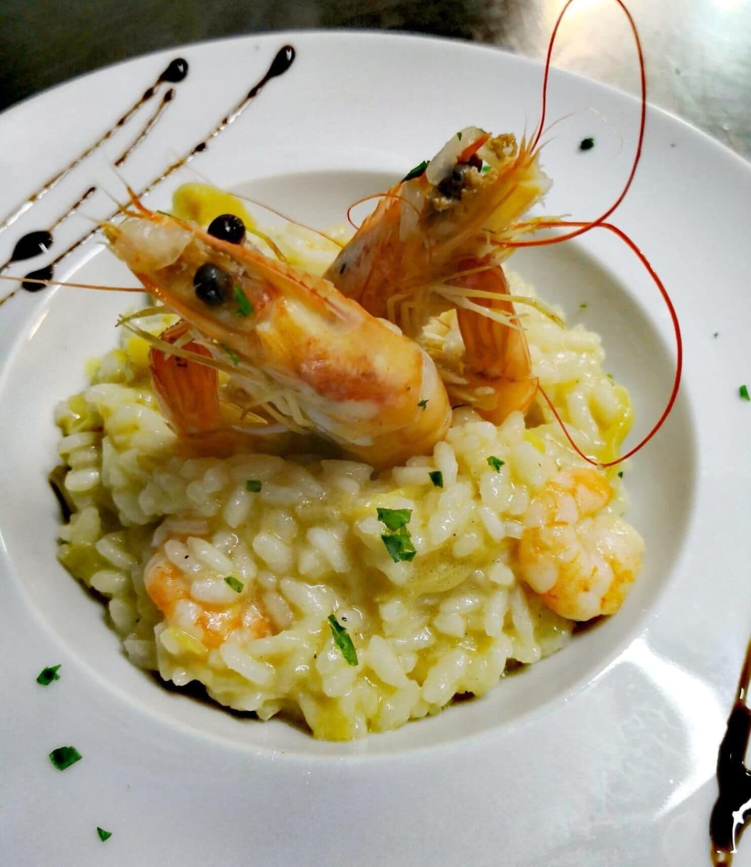 Eine Portion Risotto mit Garnelen und Dekoration.