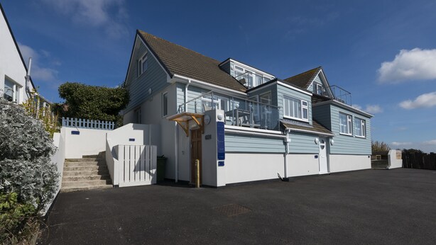 Een huis met twee verdiepingen, een veranda, een garage en een omheinde oprit.
