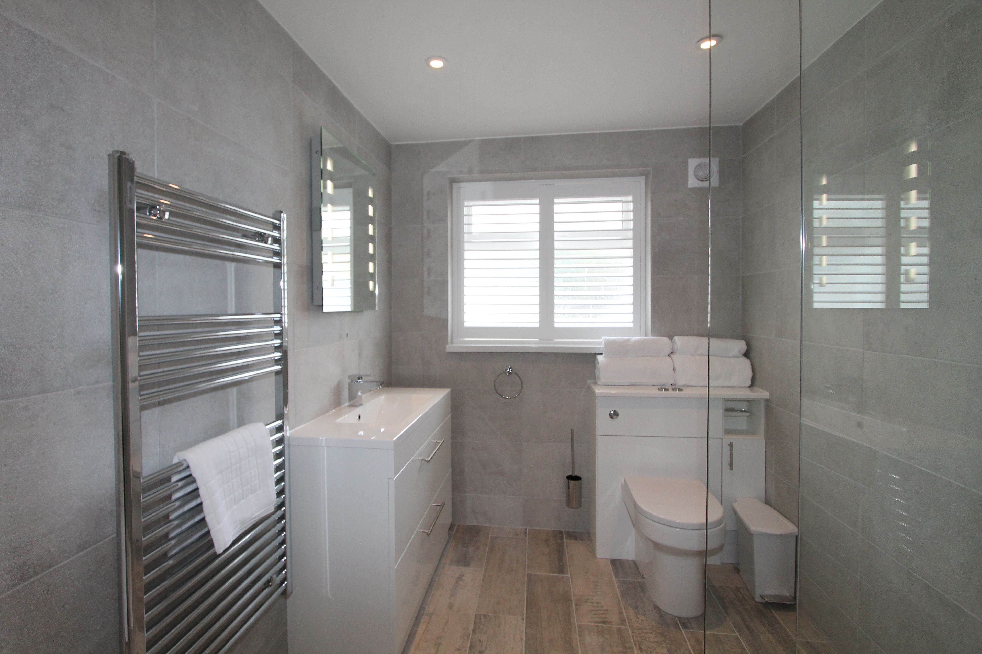 Un baño moderno con cabina de ducha de vidrio, lavamanos empotrado y retrete.