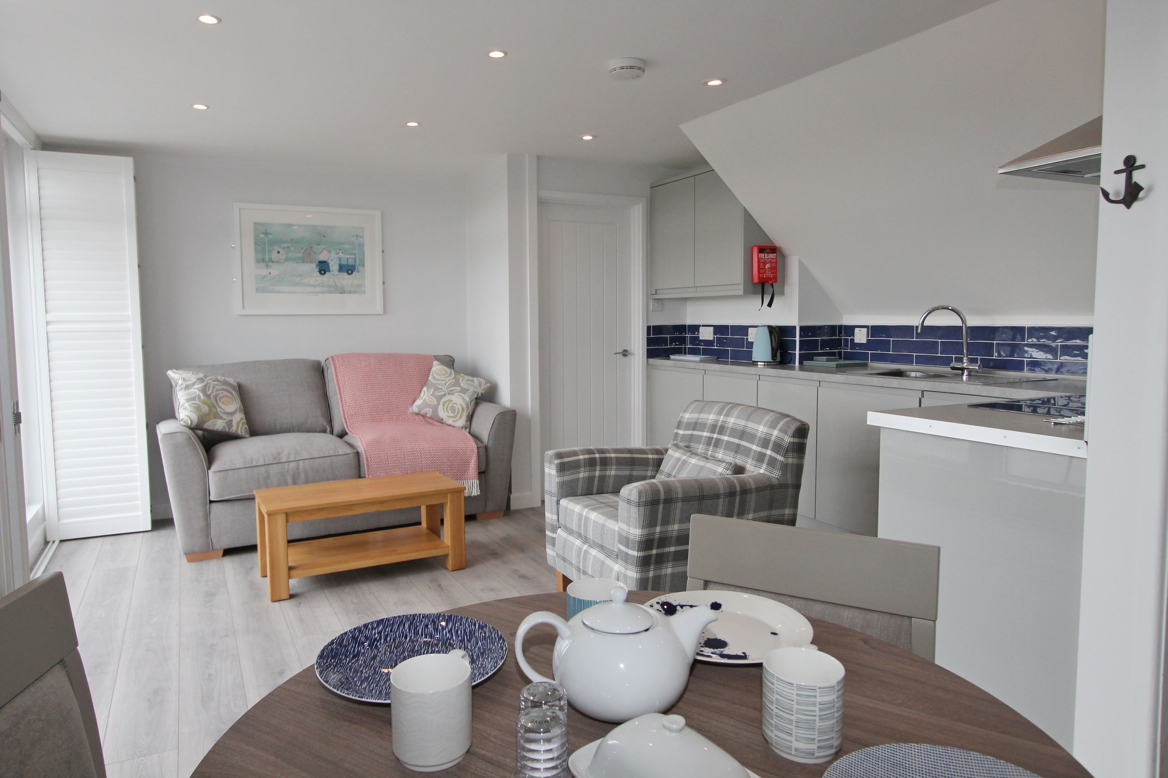 A compact living space with a kitchenette, a dining area, and a seating area with a sofa and armchairs.
