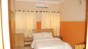 A bedroom with a bed, wooden nightstands, a wardrobe, and a chair. - Daneto Hotel (Port Harcourt)