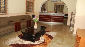 A lobby with a sofa, a coffee table, and a reception desk. - Daneto Hotel (Port Harcourt)