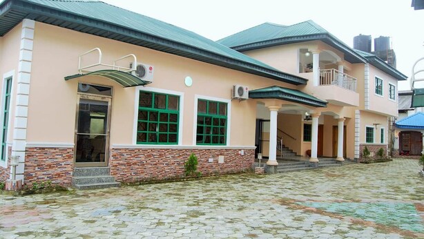A two-story building with a brick facade, green-framed windows, and a covered entrance. - Daneto Hotel (Port Harcourt)