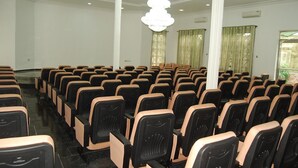 A conference room with rows of chairs, a chandelier, and large windows with curtains. - Daneto Hotel (Port Harcourt)