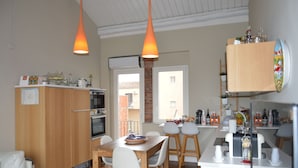 A modern kitchen with wooden cabinets, a dining area with a table and chairs, and pendant lighting. - Le 4 Leggende (Catania)