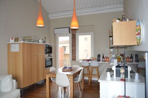 Una cucina moderna con mobili in legno, un'area pranzo con tavolo e sedie, e luci a sospensione.