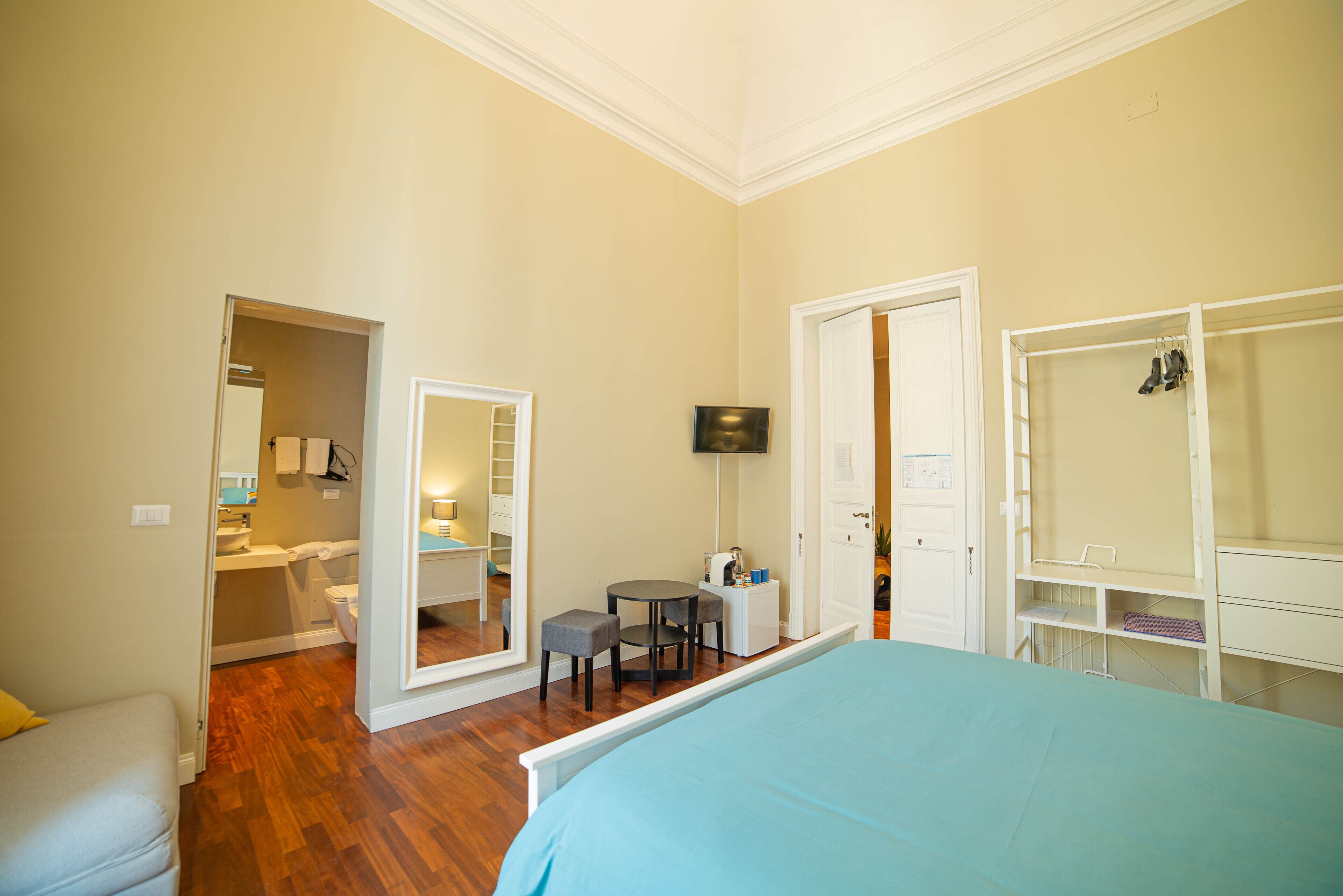 A bedroom with a bed, a desk, a chair, a TV, and a wardrobe.