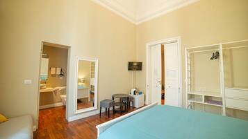 A bedroom with a bed, a desk, a chair, a TV, and a wardrobe.