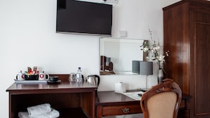 A hotel room with a wooden desk, a flat-screen TV mounted on the wall, a mirror, a cabinet, and a chair. - Oliver Twist Country Inn (Wisbech)