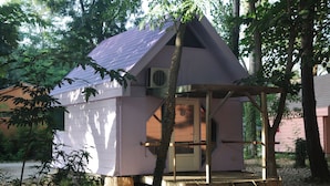 A small, single-story wooden structure with a sloped roof, surrounded by trees. - Camping BelleRive (Montfrin)
