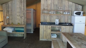 A compact kitchen with wooden walls, a microwave, a coffee maker, and a refrigerator. - Camping BelleRive (Montfrin)