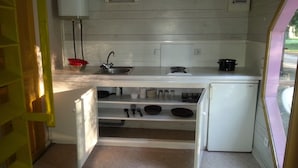A compact kitchen with a sink, stove, and storage cabinets. - Camping BelleRive (Montfrin)