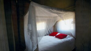 A single bed with white bedding and a red pillow, covered by a white canopy. - Camping BelleRive (Montfrin)