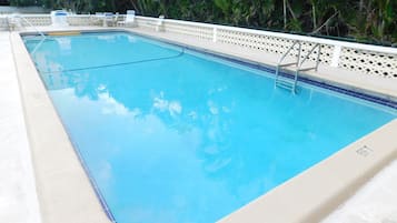 A rectangular swimming pool with a white deck and a decorative fence.