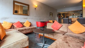 A modern living room with a sofa set, a round coffee table, and a large mirror on the wall. - Hôtel l'Ermitage (Espaly-Saint-Marcel)