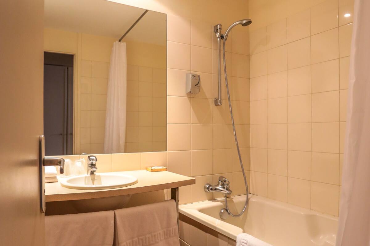 A bathroom with a sink, mirror, shower, and bathtub.