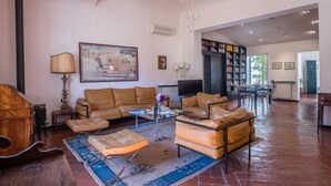 A spacious living room with a large sofa, a coffee table, and a fireplace. There is a bookshelf and a television in the room. - Santo Spirito Apartment (Florence)