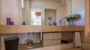 A bathroom with a large mirror, a vanity with a sink, and a towel rack. - Santo Spirito Apartment (Florence)