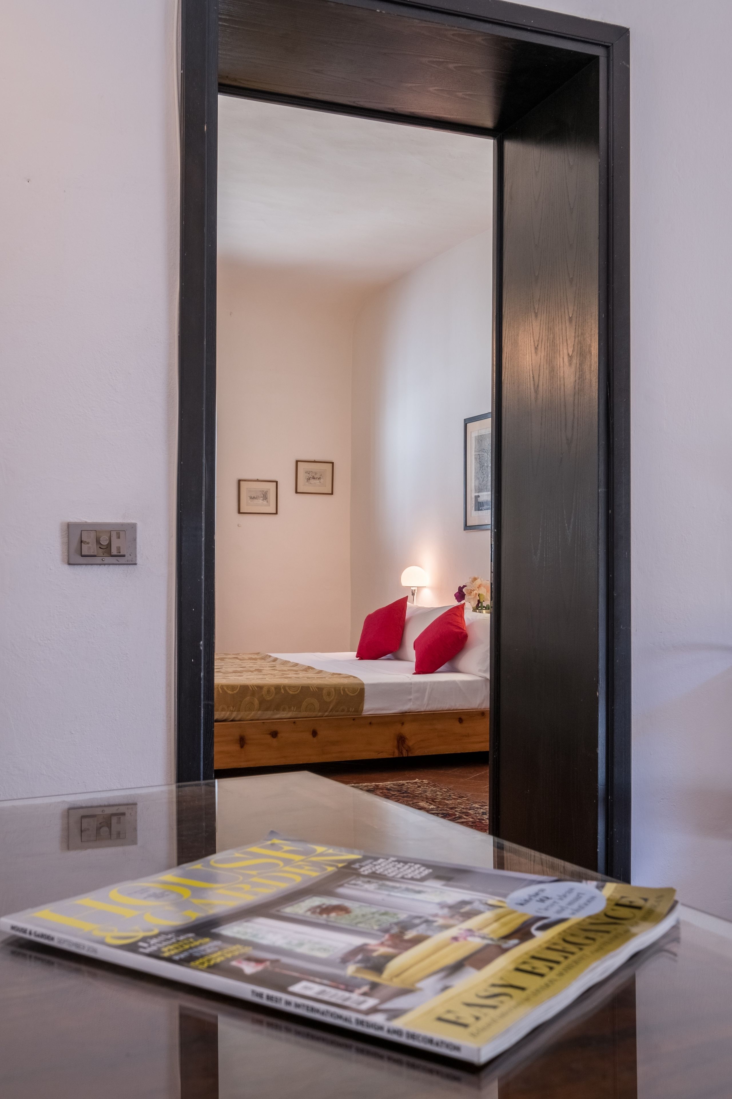 A hotel room with a bed, a nightstand, and a magazine on the table.