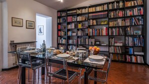 A dining area with a glass table, black chairs, and a bookshelf filled with books. - Santo Spirito Apartment (Florence)