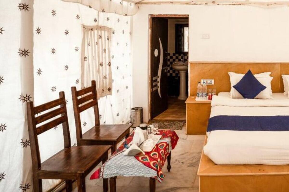 A bedroom with a bed, two nightstands, a wooden table, and chairs.